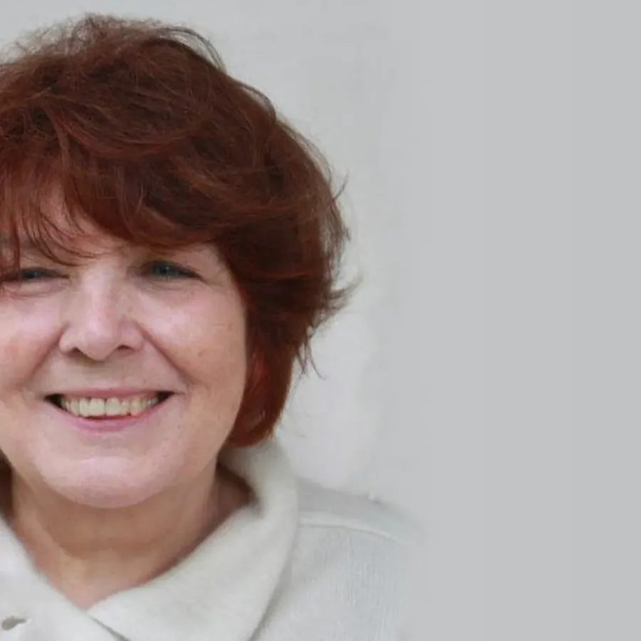 Portrait of the sculptor Jana Pfeifer with short reddish-brown hair, smiling against a light background