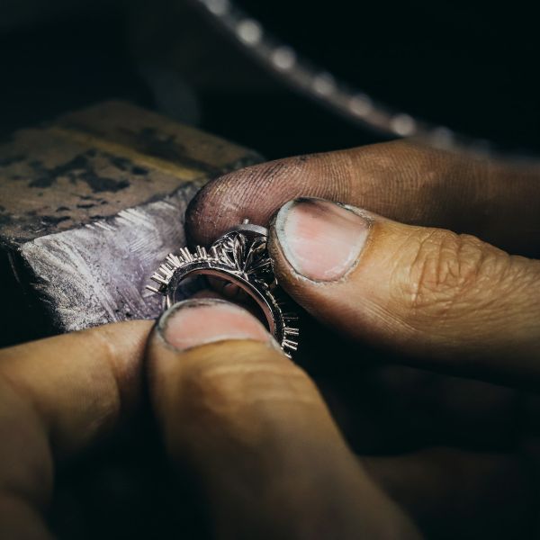 Goldschmied prüft einen filigranen Ring mit beiden Händen am Werktisch